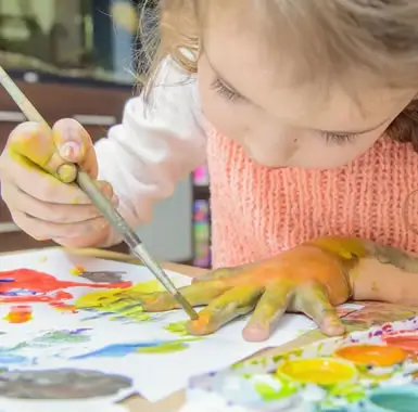kid painting yellow on her hand