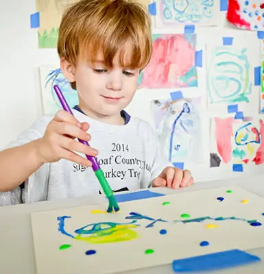 boy painting on a white canvas