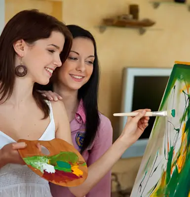 two girls painting on a canvas